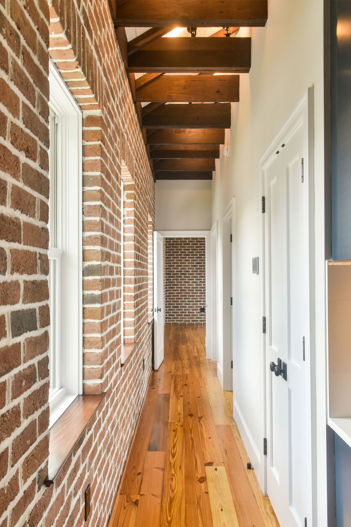 Exposed brick walls and wide plank hardwood floors create coastal charm in this historic home