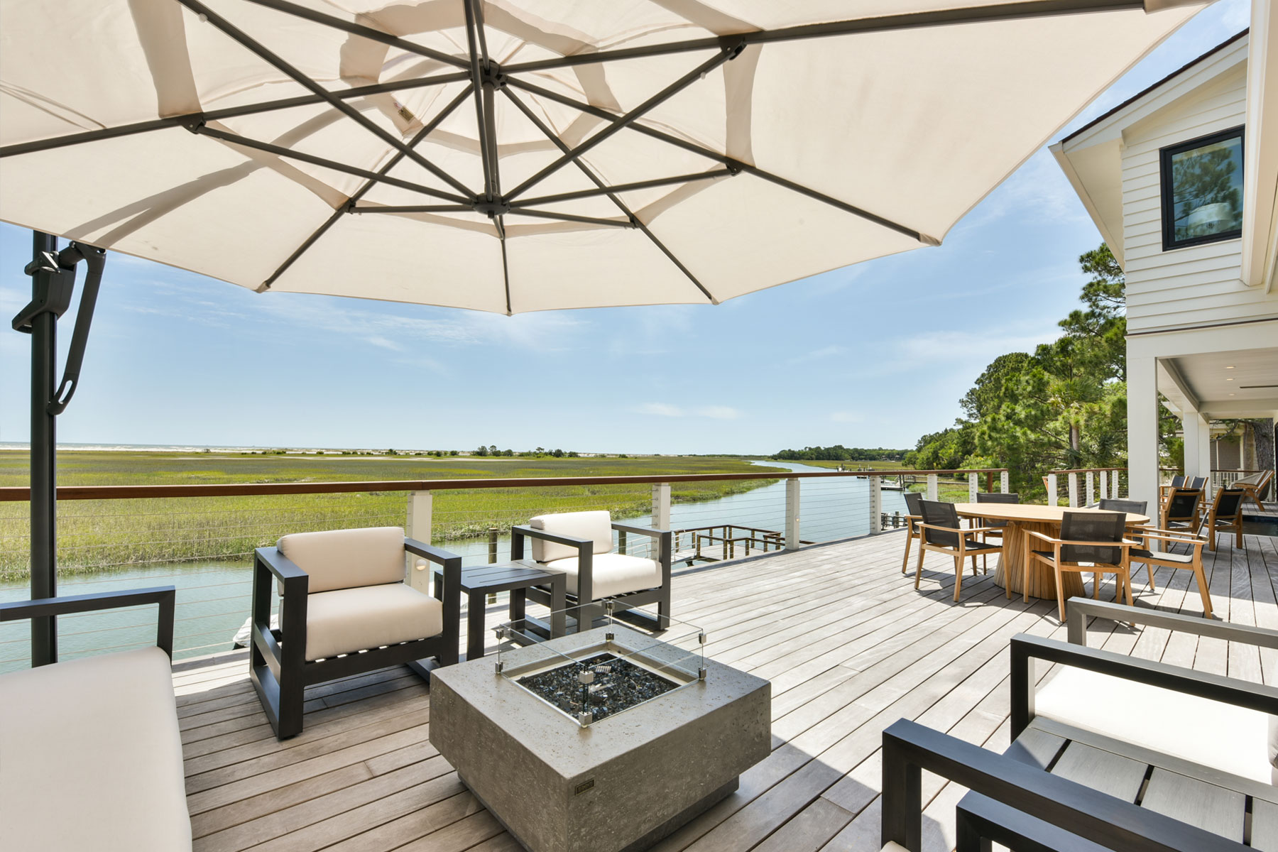 Elevated outdoor deck withlarge lounge, dining, and pool with marsh views