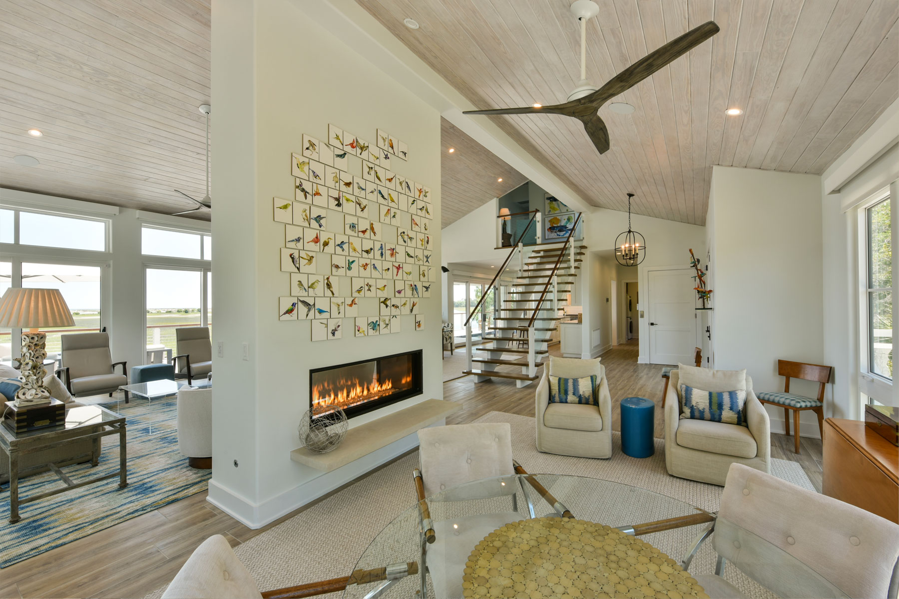 Double-sided fireplace separting game room and living room in coastal modern renovation of Seabrook Island home