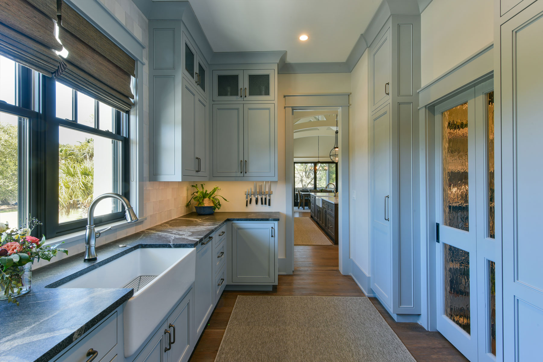 Butler's kitchen in luxury home with light blue painted custom cabinets and walk in pantry. View back to kitchen.