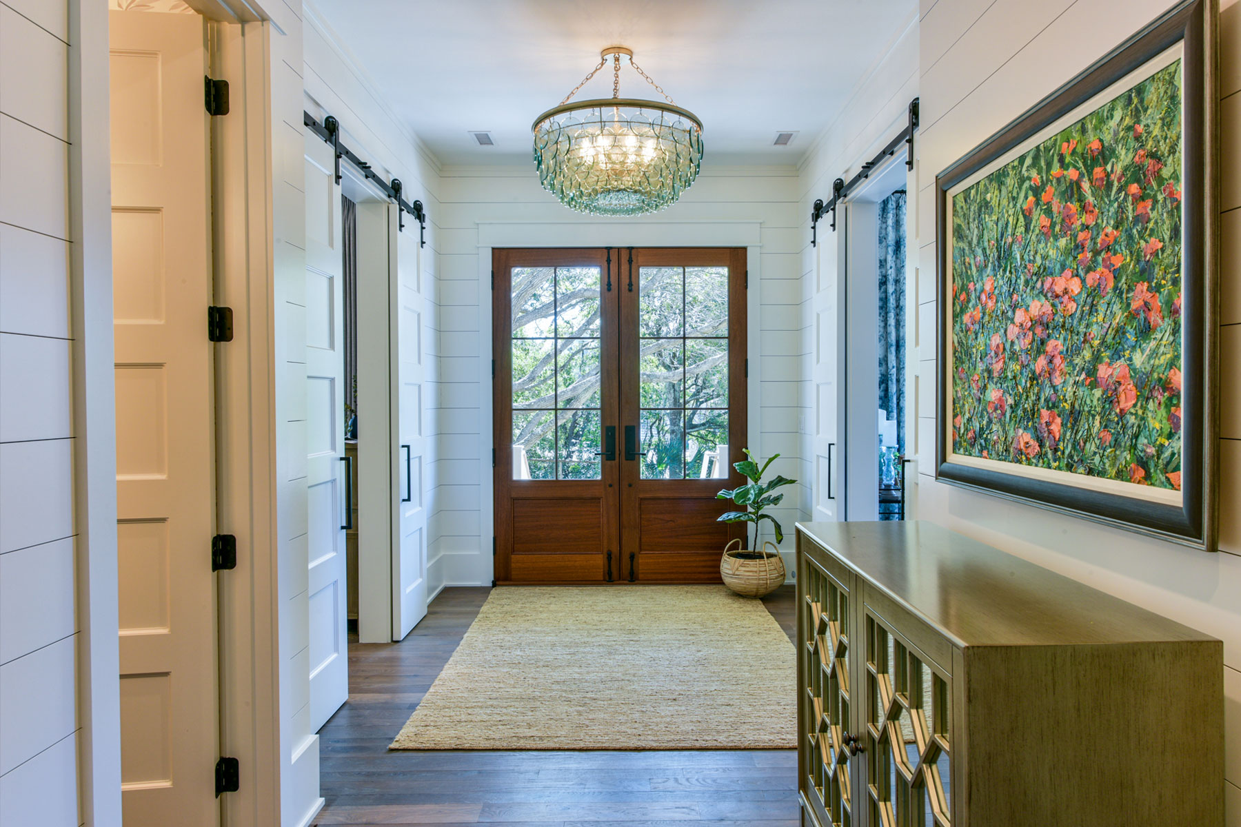 Front entry hall with wood stained doors, custom light fixutres, dark wood floors and nickel gap wall treatments