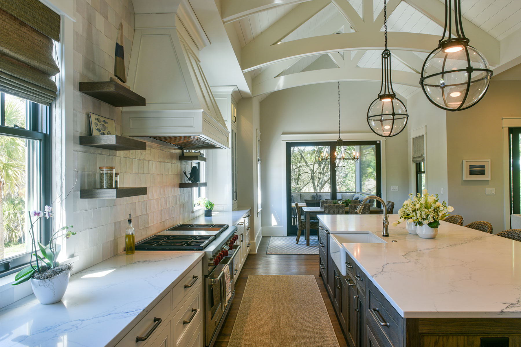 Entertaining kitchen with trussed ceiling open to living room with adjacent screened porch
