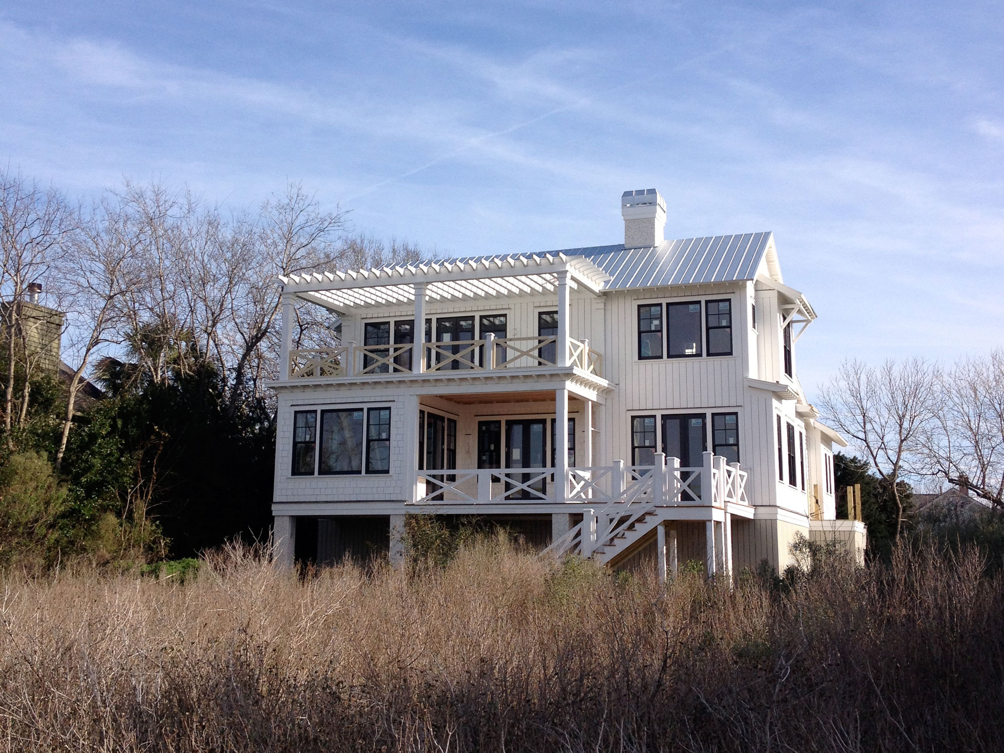 Backside view of coastal home with porches and metal room