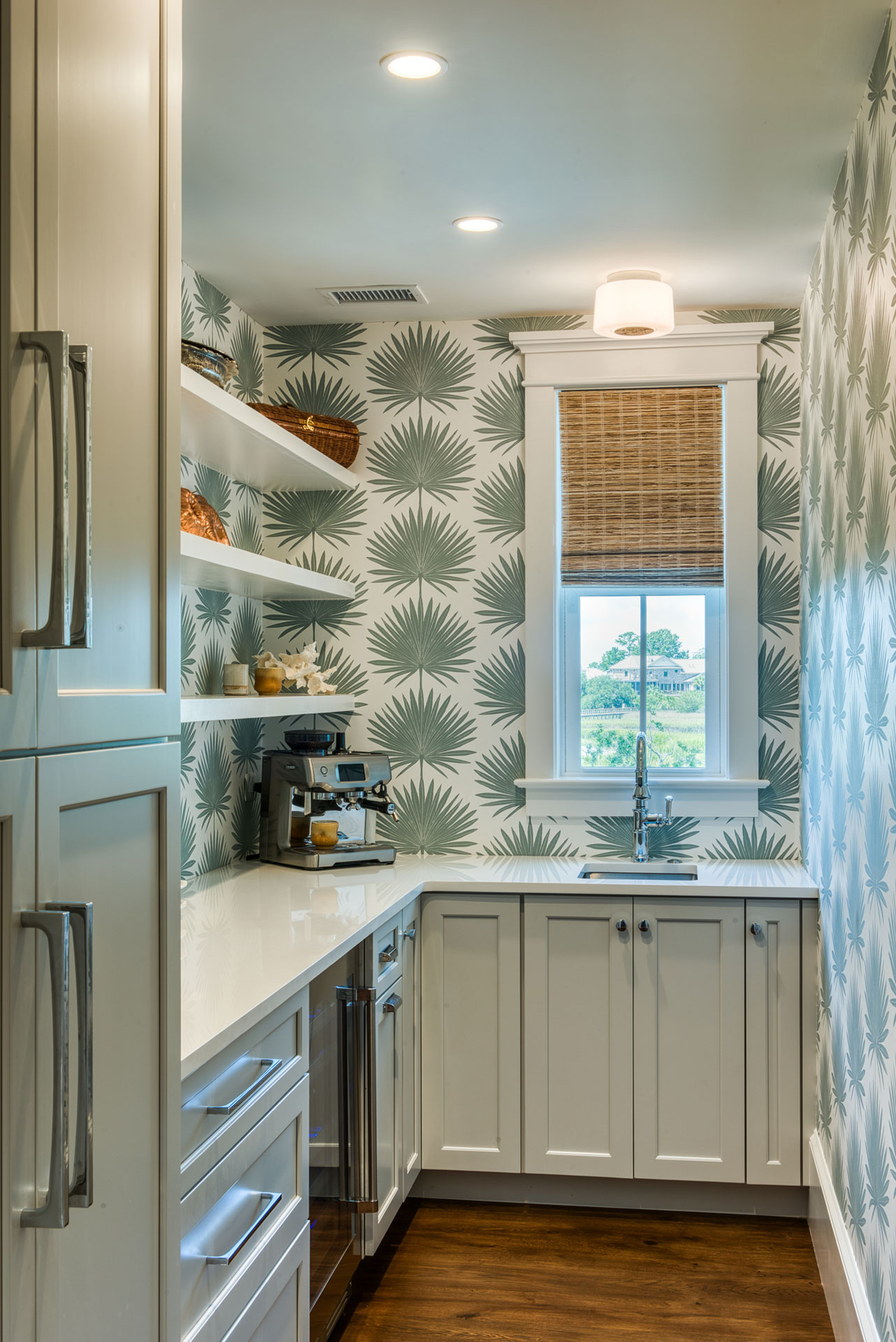 Walk-in butler's pantry off main kitchen with bold wallpaper and custom cabinets