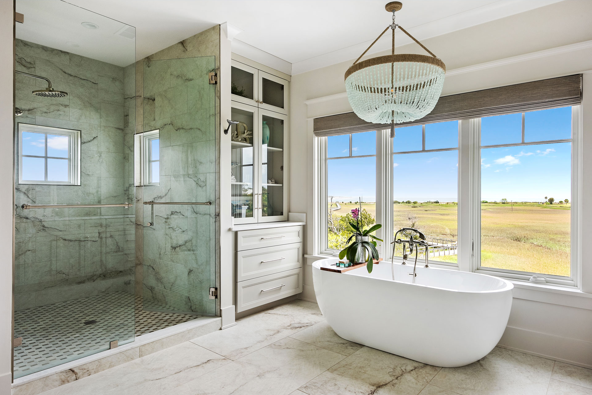 Master bathroom with large shower and standalone tub with views of the marsh and ocean