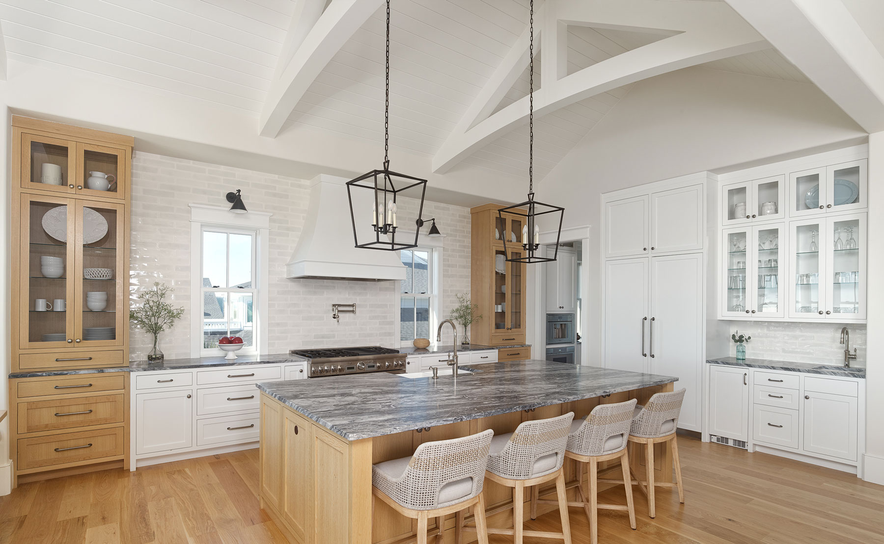 Large, luxury coastal kitchen with custom oak and painted white cabinets, center island, hidden appliances and back kitchen