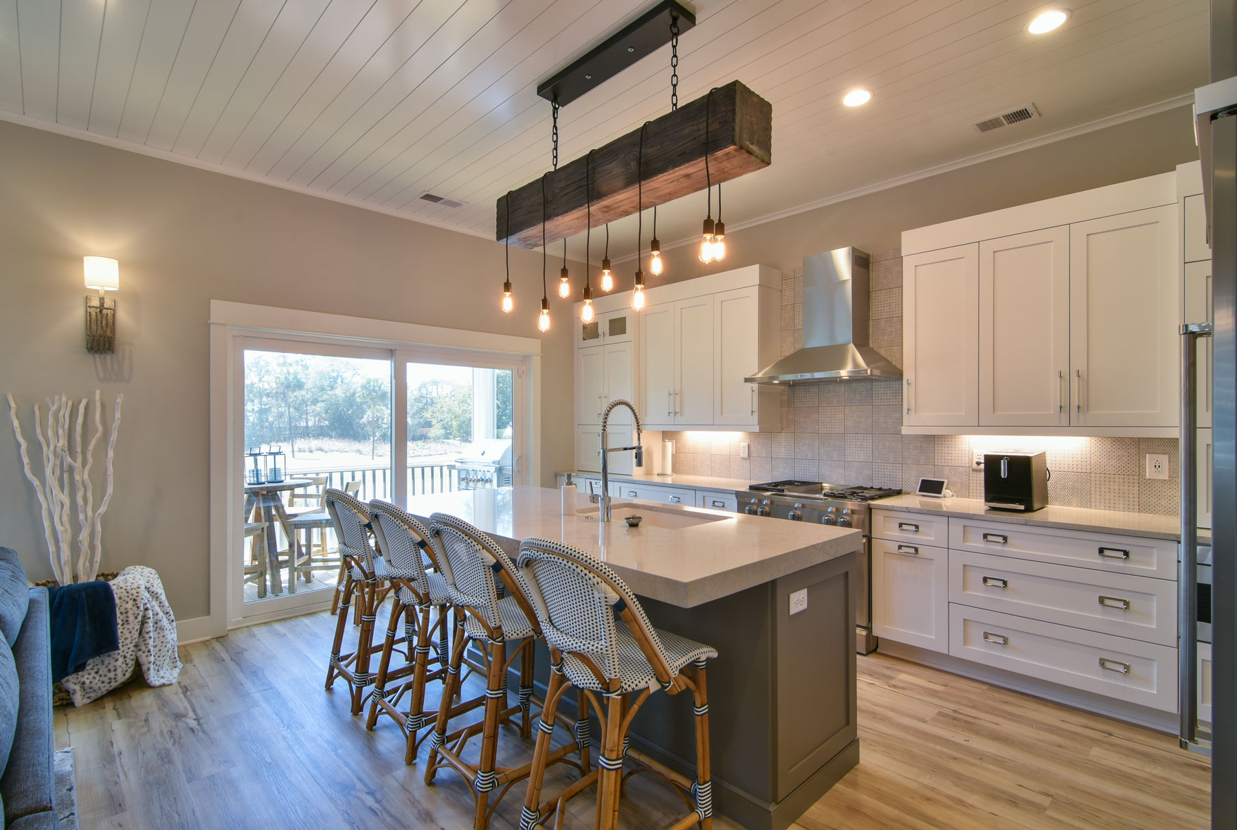 Open plan kitchen and family room, large island. White cabinets, navy blue island.