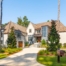 Custom designed luxury home with European influences and modern touches on elevated coastal home with stucco exterior and gray painted window dormers.