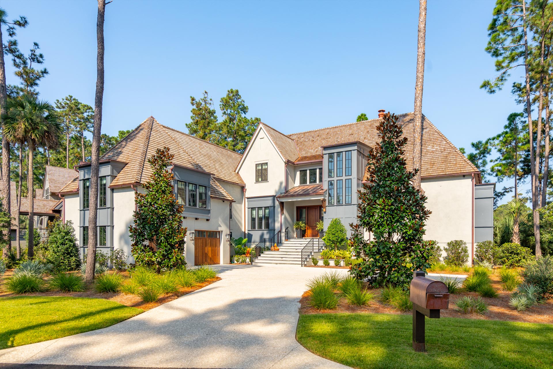 Custom designed luxury home with European influences and modern touches on elevated coastal home with stucco exterior and gray painted window dormers.