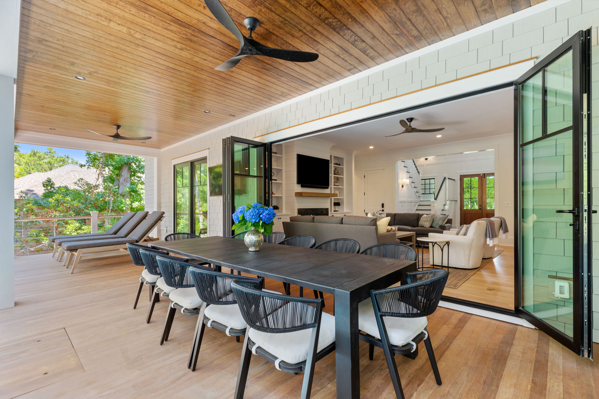 Accordian doors open to covered porch with wood clad ceiling in new construction home on Kiawah Island